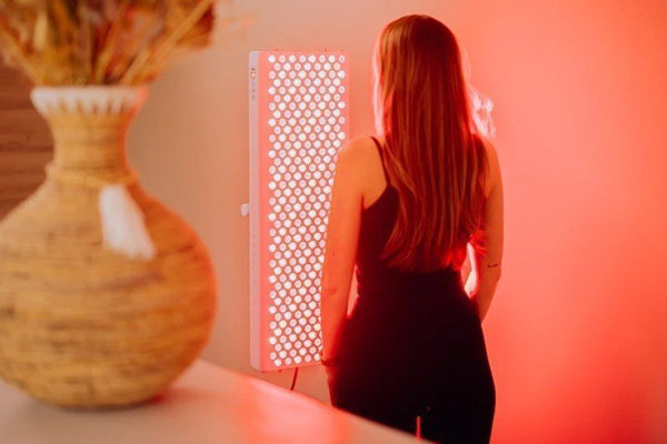 Vrouw staat met haar rug naar de camera voor een brandend rood licht therapie paneel