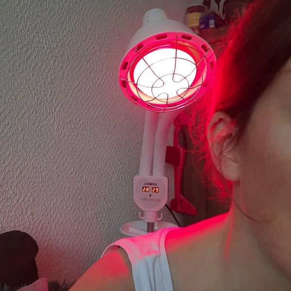 Vrouw belicht haar schouder en nek met de dubbele kop infraroodlamp van Liroma