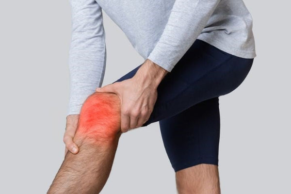 Man in sportkleding grijpt naar zijn knie, met een rode gloed die een ontsteking aangeeft