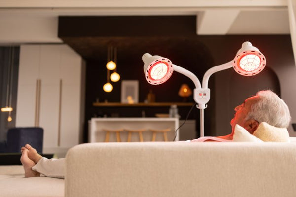 Man ontspant op de bank onder een infraroodlamp met twee rood gloeiende koppen