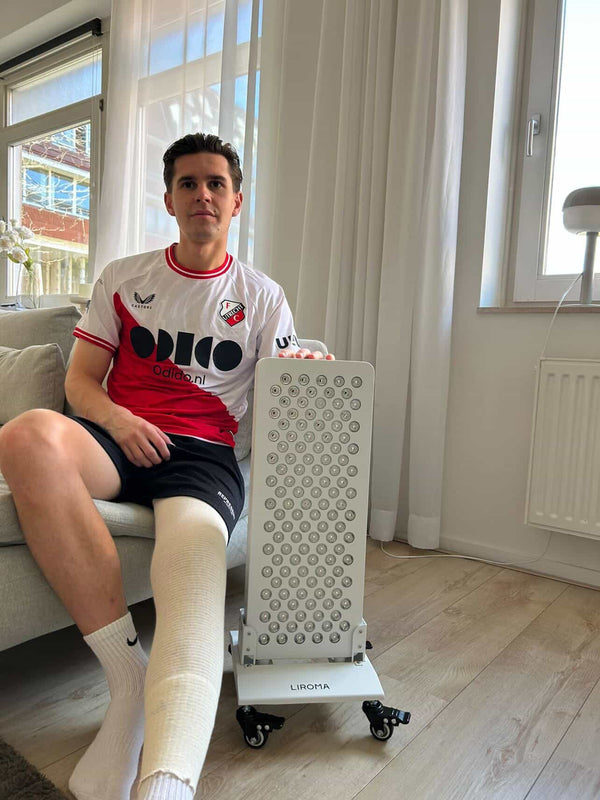 Man met gipsverband om zijn onderbeen zit op de bank naast een Liroma paneel op een standaard