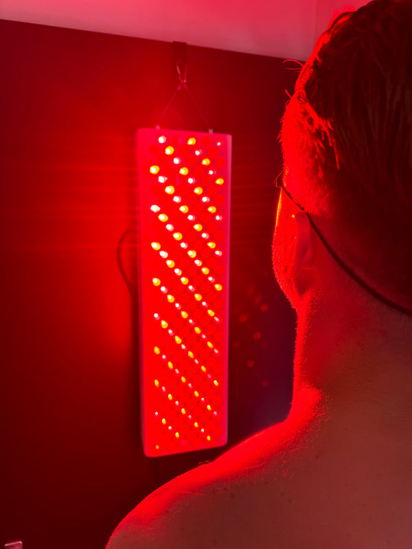 Man kijkt naar een smal Liroma roodlichtpaneel dat aan de muur hangt en de kamer rood kleurt