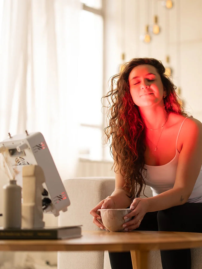 Vrouw gebruikt de Liroma Compact rood licht lamp thuis aan tafel