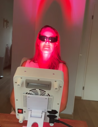 Vrouw met beschermbril zit voor een wit Liroma paneel dat haar gezicht in rood licht zet