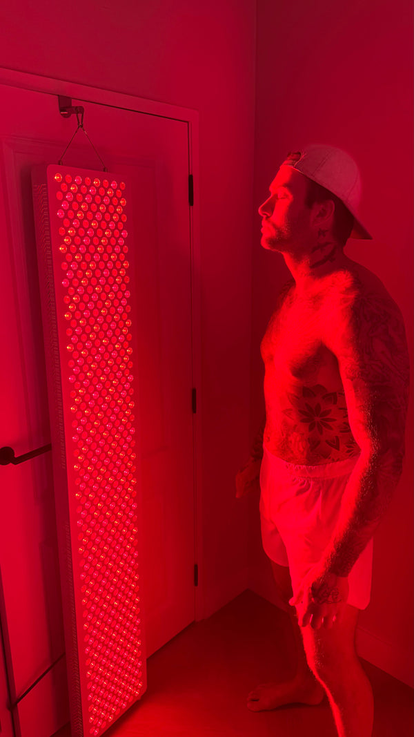 Man met pet staat naast een groot Liroma roodlichtpaneel dat aan de deur hangt