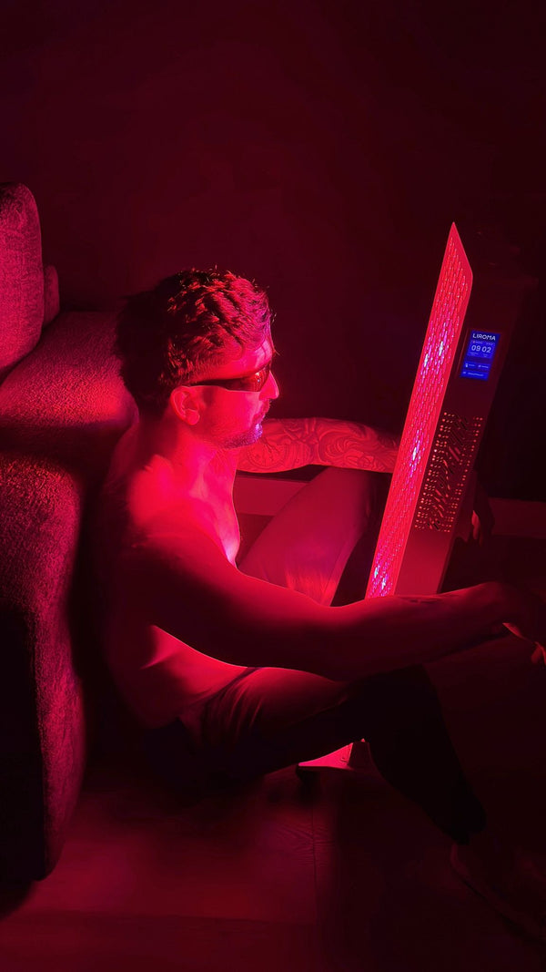 Man met beschermbril zit op de vloer voor een smal Liroma paneel met display in een donkere kamer