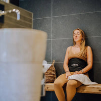 Vrouw ontspant op een bankje met de Liroma HeatPULSE infrarood rugband om haar middel