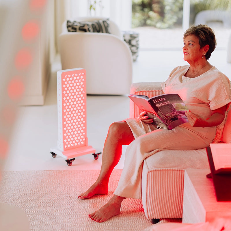 Vrouw leest naast de Liroma Advanced rood licht therapie lamp in de woonkamer