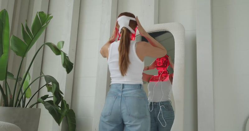 Vrouw zet het Liroma GLOW LED masker op voor de spiegel, het rode licht staat aan